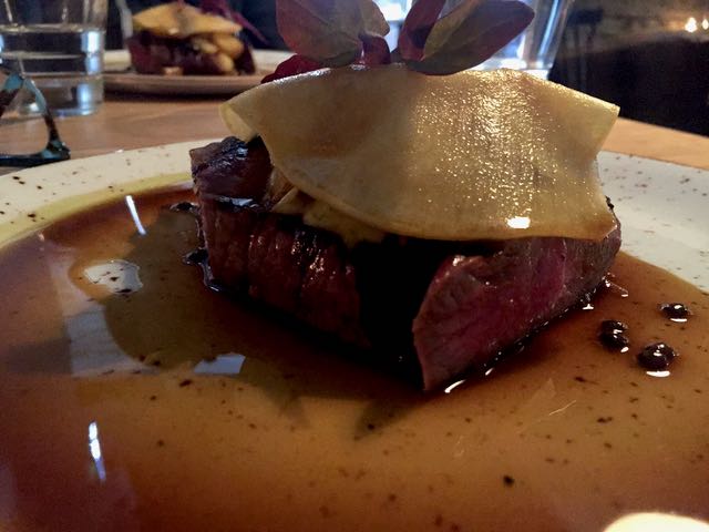 Pääruokana Agnus-filet pihvi. Sen päällä on ohuen ohut viipale lanttua ja alla pihvin lisäksi belugalinssejä ja perunaa.
